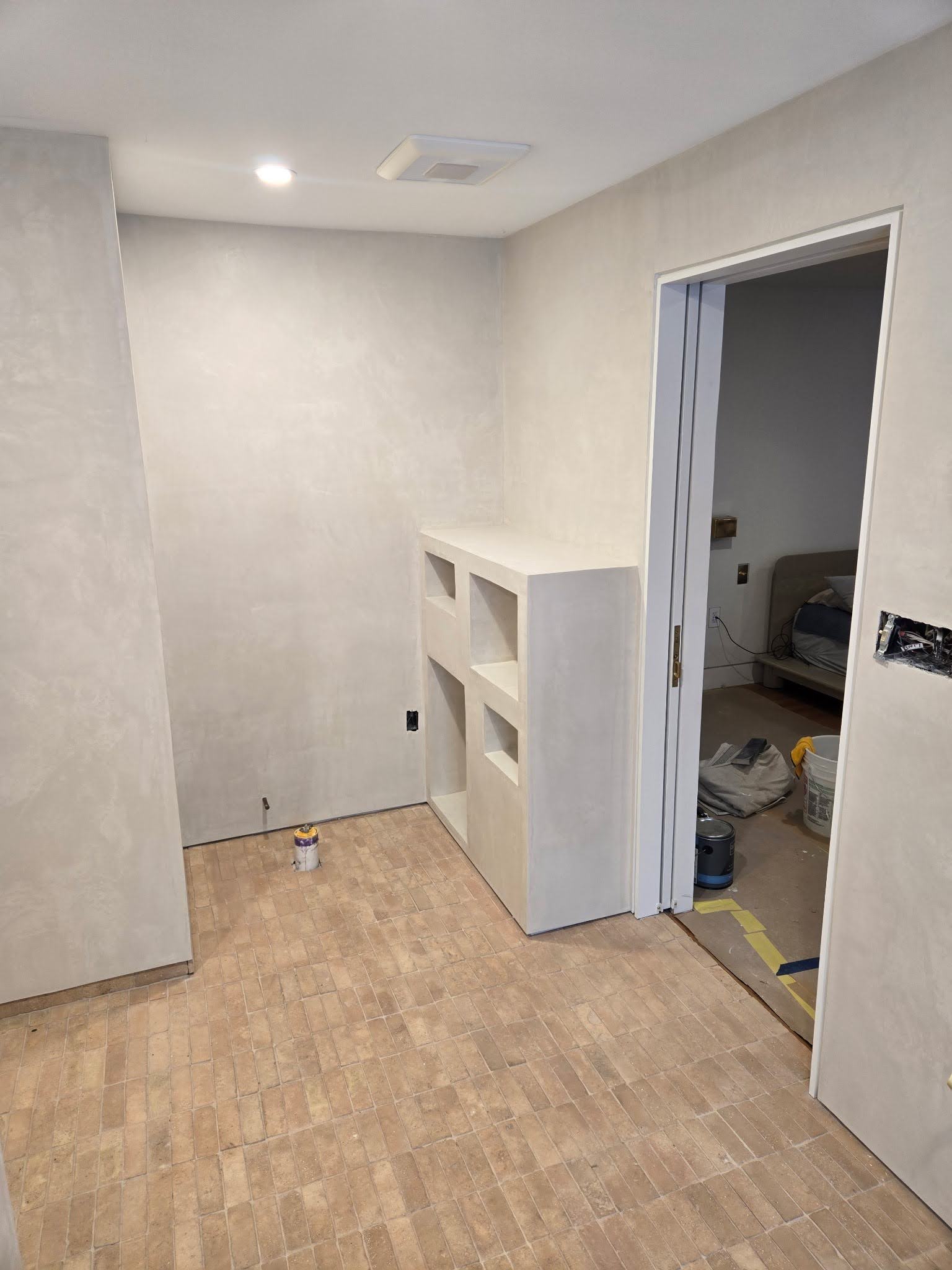 Built-in open shelving unit formed and finished in microcement, with tools still on site