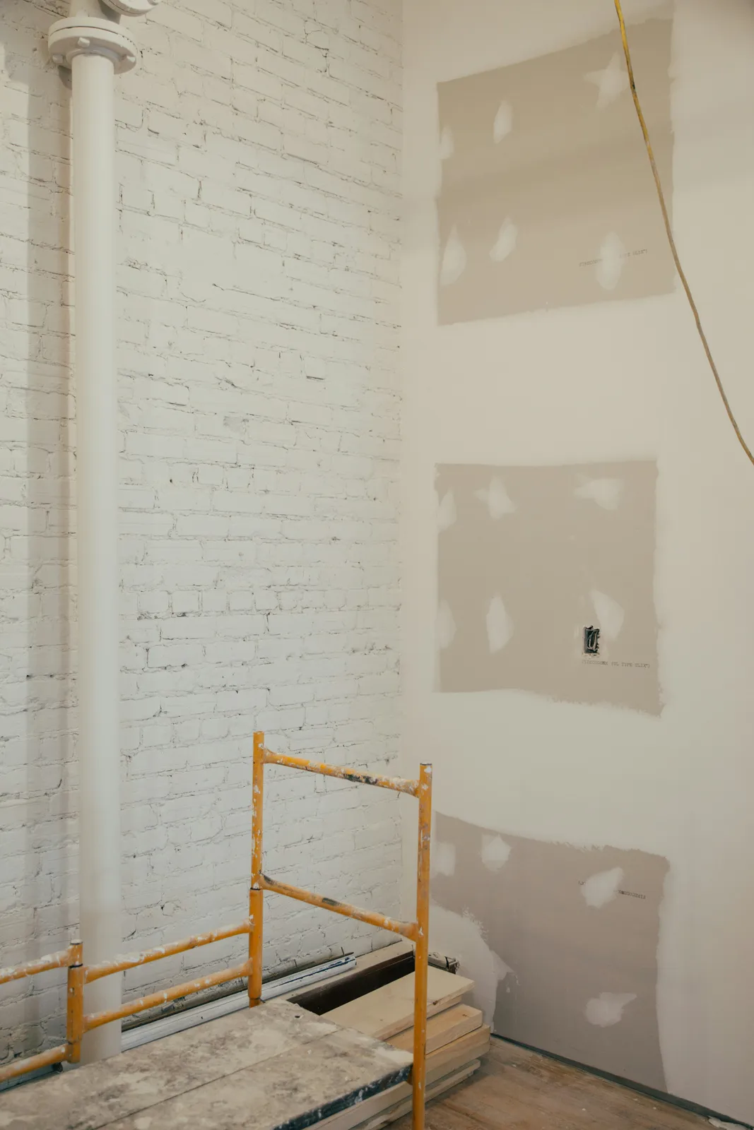 Drywall panels taped and jointed, with fresh compound over the seams and fixings