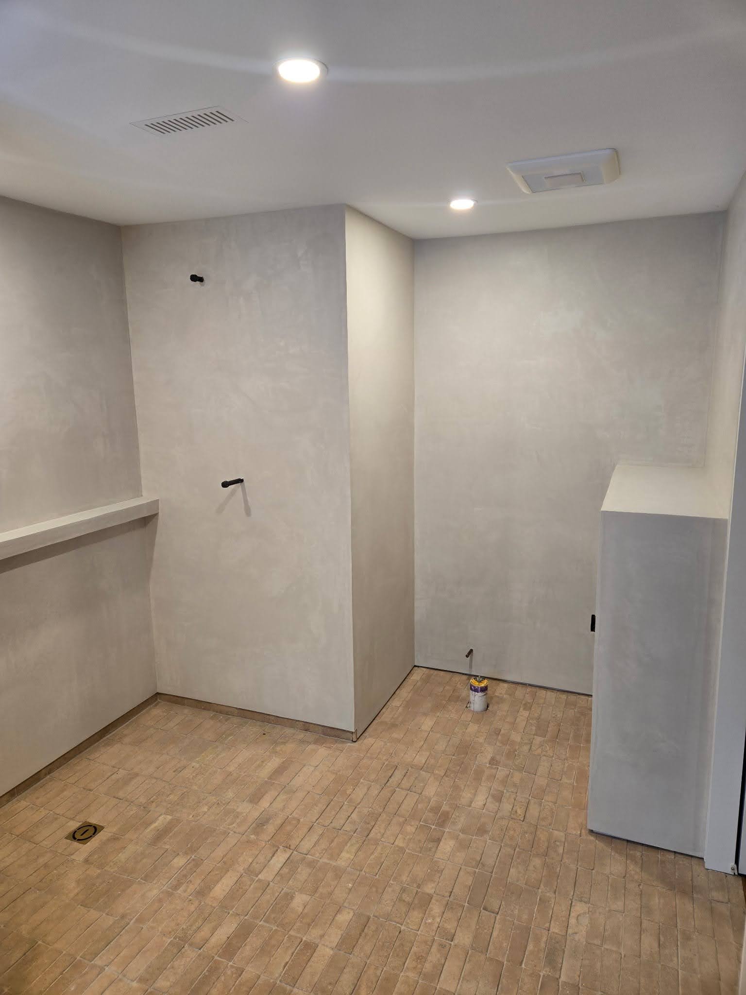 Wet room finished in seamless microcement, with a formed bench and no tile joints