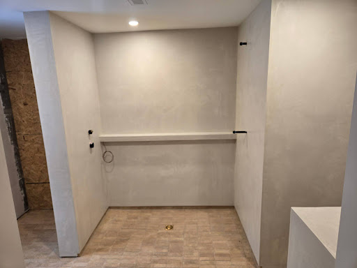 Shower area finished in microcement with a long formed shelf and no tile joints